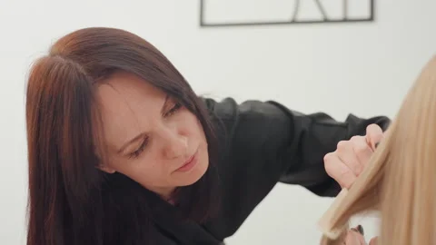 Expert guides apprentice through haircut techniques, Collaborative teaching Video stock 333649333