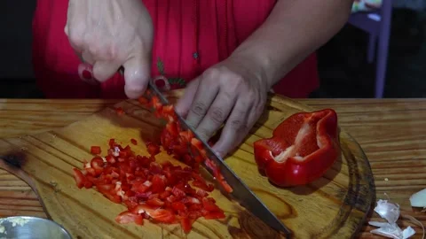 Expert hands chopping vibrant red bell peppers on wood Stock Footage 313846499
