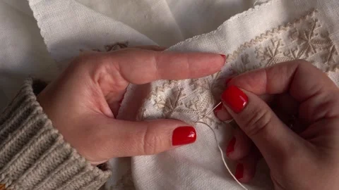Expert hands create delicate embroidery on a cream fabric Stock Footage 311445443