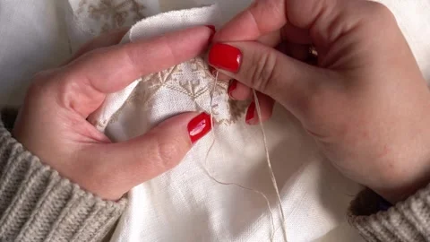 Expert hands create delicate embroidery on a cream fabric Stock Footage 314653783