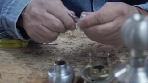 An expert in key duplication, examines a piece for lock repair and Stock Footage 277019614