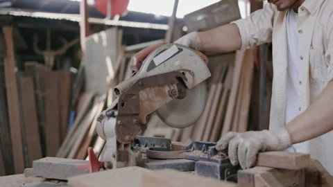 Expert male carpenter active is using electric machine sawing wood Stock Footage 249984016