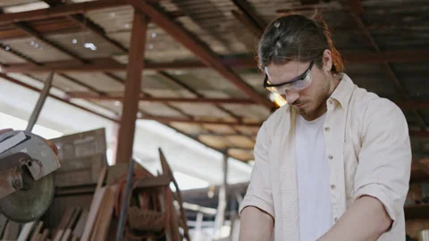 Expert male carpenter active is using electric machine sawing wood Stock Footage 249984025