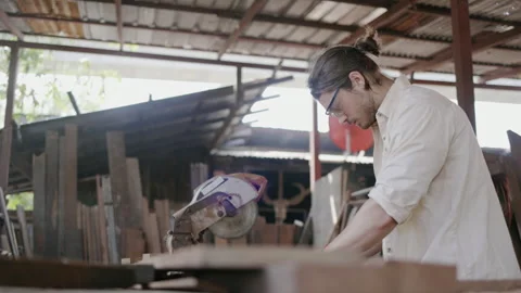Expert male carpenter active is using electric machine sawing wood Stock Footage 249984090