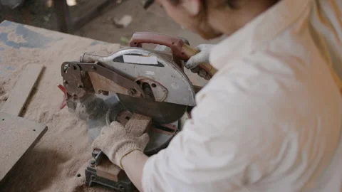 Expert male carpenter active is using electric machine sawing wood Stock Footage 249984147