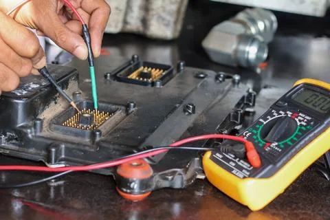 Expert mechanic using multimeter probes to diagnose car engine electronic c.. 库存照片