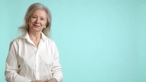 Expert Senior Lady Demonstrating Space for Your Ad, Light Blue Background Stock Footage 267731786