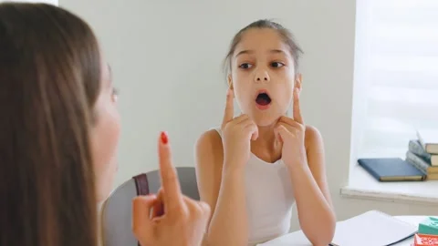 Expert speech therapist interacts with young girl during a therapy session Stock Footage 315541324