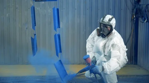 Expert is using a spraying gun to paint metal pieces at a painting factory Stock Footage 123430440