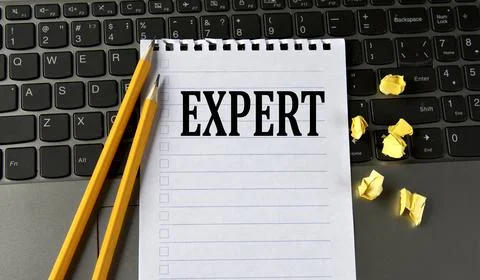 EXPERT - word in a white notepad on the background of a laptop with pencils Stock Photos