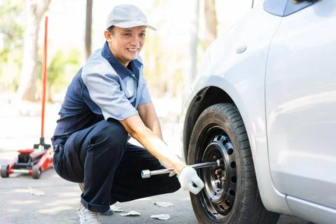 Expertise mechanic man  in uniform using force trying to unscrew the wheel bo Foto stock