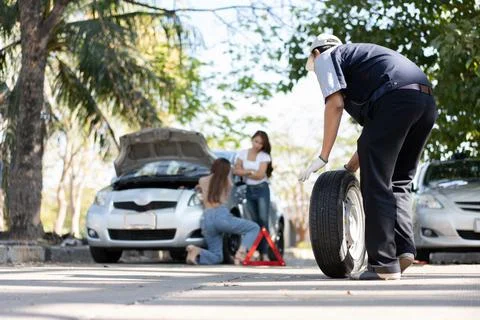 Expertise mechanic man  in uniform using force trying to unscrew the wheel .. Stock Photos