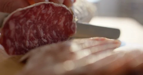 Experts hand is cutting thinly sliced a seasoned Parma salami. Stock-Footage 115327316