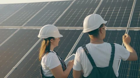 Experts study the operation of a solar power plant while walking around the farm Stock Footage 256835181