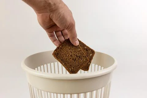 Expired bread is thrown into the trash. Processing of food waste. Stock Photos