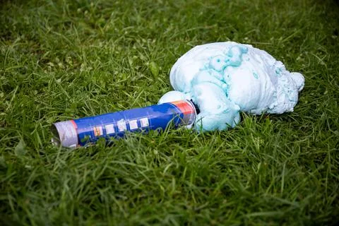 An exploded cylinder with construction foam on the grass. Balloon defect, close Stock-Fotos