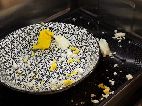 Exploded egg in microwave, cleaning concept and food safety awareness. Stock Photos