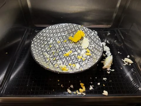 Exploded egg in microwave, cleaning concept and food safety awareness Stock Photos