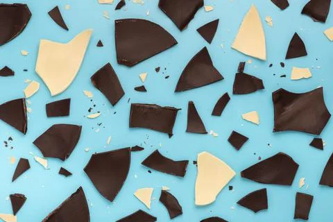 Exploded white and dark chocolate Easter eggs over blue background, holiday c 스톡 사진