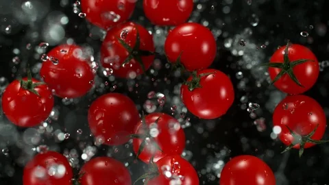 Exploding cherry tomatoes with water on a black background. 스톡 동영상 120374076