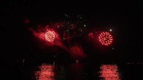 Exploding fireworks illuminate the dark night sky with the moon visible, 스톡 동영상 343278015