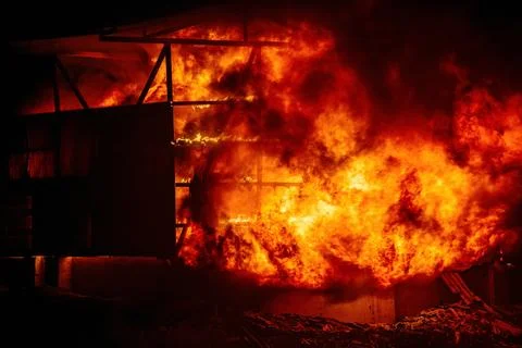 Exploding warehouse. Burning industrial building. Big blaze at night Stock Photos