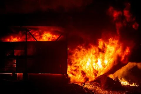 Exploding warehouse. Burning industrial building. Big blaze at night Stock Photos