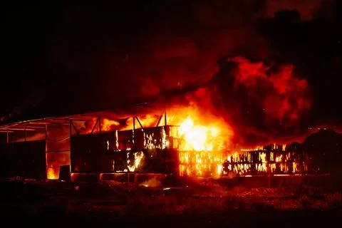 Exploding warehouse. Burning industrial building. Big blaze at night Stock Photos