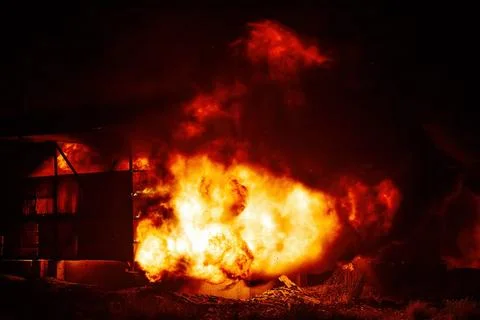 Exploding warehouse. Burning industrial building. Big blaze at night Stock Photos