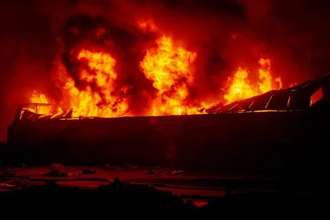 Exploding warehouse. Burning industrial building. Big blaze at night Stock Photos