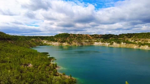 Exploration of a deep blue lake surrounded by green hills and thick clouds in an 動画素材 340448180