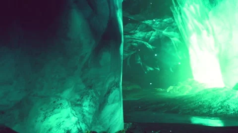 Exploration of a green lit ice cave with glowing reflections in water Stock Footage 344128093