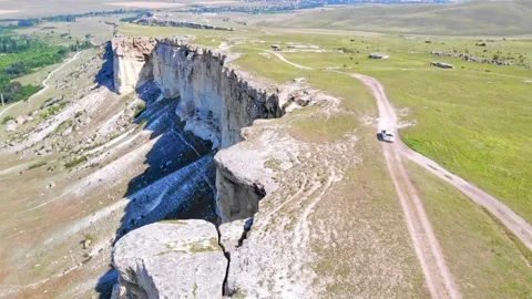 Exploration white car drive along the edge of a rocky white limestone mountain Видео 339439721