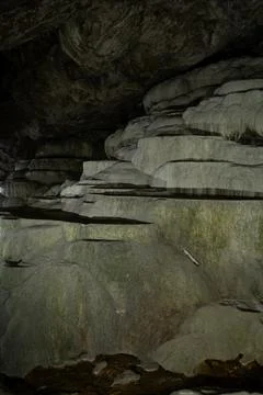 Explore Ancient Rock Formations Within a Dimly Lit Cave Featuring Layered Stone Stock Photos