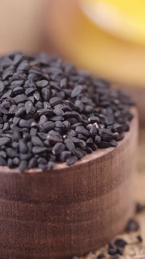 Explore black cumin seeds in a wooden bowl on a table Video stock 336881392