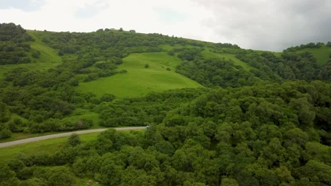 Explore lush green hills and winding roads in a serene countryside landscape Stock Footage 284672263