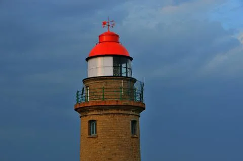 Explore a red and tan brick lighthouse against a dramatic cloudy blue sky Stock Photos