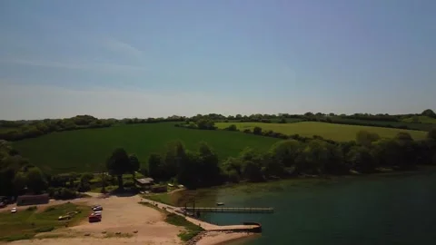 Explore a riverbank with green fields and water during a sunny day in a rur.. Stock Footage 339932258