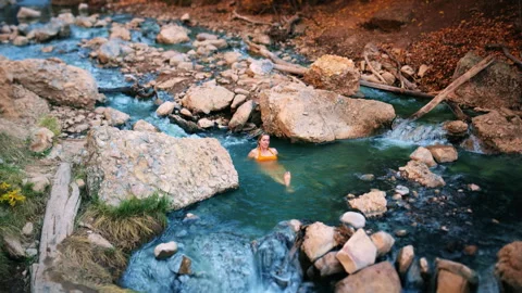 Explore a serene hot spring pool surrounded by autumn colors and flowing wate Stock Footage 310217539