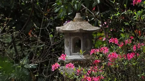 Explore a tranquil garden with a stone lantern surrounded by vibrant flowers  Stock Footage 296113820