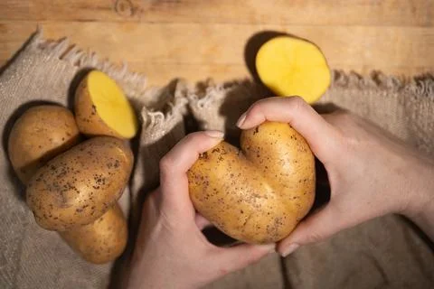 Explore the Unique Potato Shapes in Hands Set Against a Beautiful Rustic 写真素材
