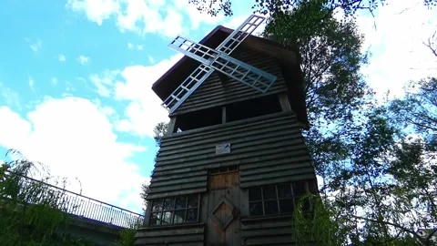Explore a wooden windmill structure among trees under a clear sky in a rural are Stock Footage 325626235