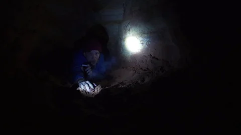 Explorer deeply breathing takes flashlight which lies on ground in cave Stock Footage 80063187
