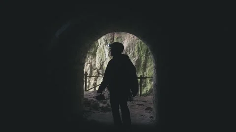 Explorer Emerges: Journey Through a Dark Cave Passage Video stock 332073243