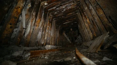 The explorer with a flashlight walks along an old abandoned mine with rails Stock Footage 86074275