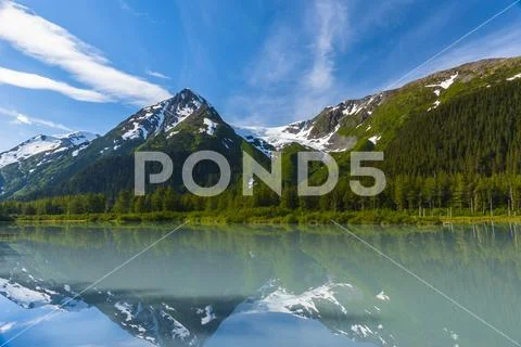 Explorer Glacier is seen reflecting in the calm silty waters of Explorer Lake on Stock Photos