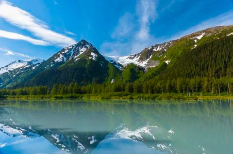 Explorer Glacier is seen reflecting in the calm silty waters of Explorer Lake on Stock Photos
