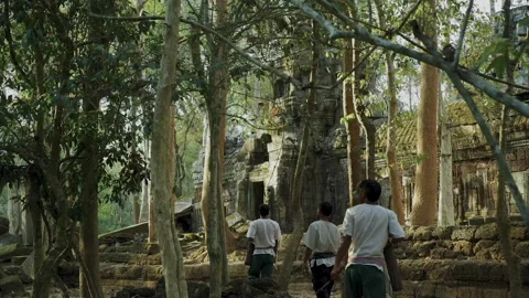 Explorer guiding locals through ancient Cambodian jungle ruins 库存影片 331946843