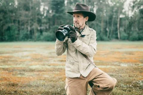 Explorer with hat in the field holding camera. Stock Photos