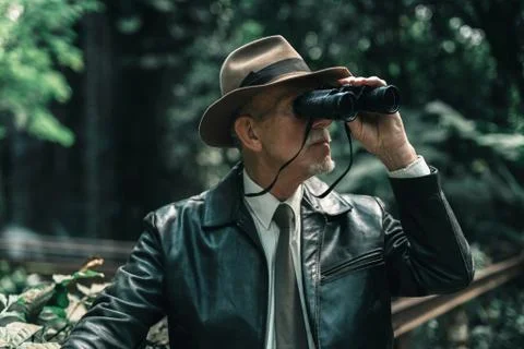 Explorer with hat in jungle looking through binoculars. Stock Photos